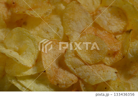 Crispy golden potato chips scattered on a white plate, inviting snack time bliss Crispy golden potato chips scattered on a white plate, inviting snack time bliss 133436356