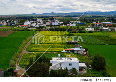 Rolling green fields and charming villages flourish under cloudy skies in tranquil countryside vistas of a rural landscape Rolling green fields and charming villages flourish under cloudy skies in tranquil countryside vistas of a rural landscape 133436631