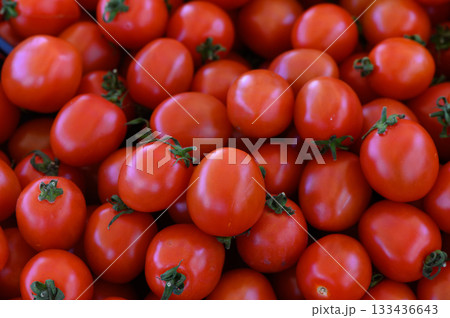 Vibrant red tomatoes piled high at a bustling farmers market, inviting shoppers on a sunny afternoon Vibrant red tomatoes piled high at a bustling farmers market, inviting shoppers on a sunny afternoon 133436643