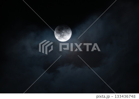 Full moon shining through soft clouds in the blue night sky 133436748