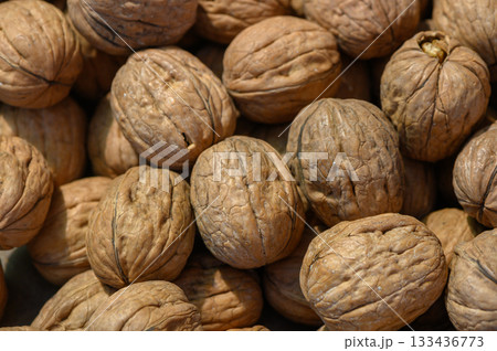 Natural beauty of sun-dried walnuts gathered on a wooden table in a rustic kitchen setting 133436773
