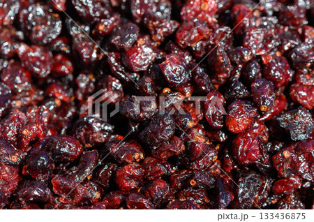 Vibrant and glossy dried cranberries glisten under the sun, showcasing their rich color in a market setting during the harvest season 133436875