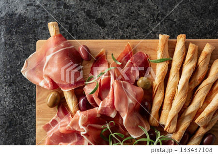 Italian prosciutto with bread sticks, olives, and rosemary. Italian prosciutto with bread sticks, olives, and rosemary. 133437108