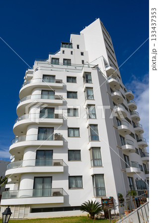Modern architectural marvel rises against a clear blue sky, showcasing its unique curves and a vibrant urban landscape 133437353