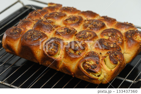 Deliciously baked cinnamon rolls cooling on a baking rack in a cozy kitchen just before serving as a sweet morning treat 133437360