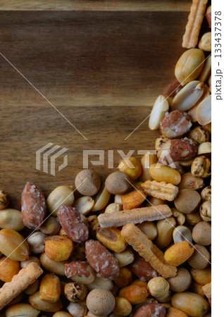 Colorful assortment of mixed nuts and snacks displayed on a wooden platter for an inviting party atmosphere 133437378