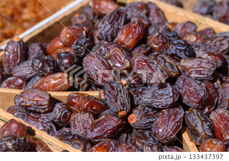 Sun-kissed dates showcased in a vibrant market during late afternoon hours, inviting passersby to indulge in their rich sweetness and health benefits 133437397