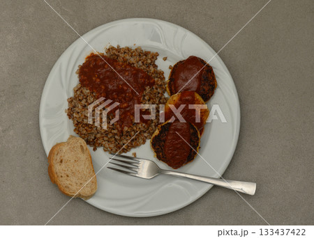 Deliciously prepared bulgur wheat served with savory meat patties and tangy sauce on a minimalist plate at a cozy kitchen table Deliciously prepared bulgur wheat served with savory meat patties and tangy sauce on a minimalist plate at a cozy kitchen table 133437422