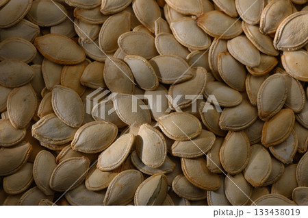 Countless pumpkin seeds glisten in the warm afternoon light, celebrating the harvest season with their earthy hues and intricate shapes Countless pumpkin seeds glisten in the warm afternoon light, celebrating the harvest season with their earthy hues and intricate shapes 133438019