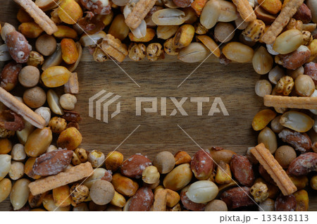 Colorful assortment of nuts and snacks creates a rustic frame on wooden table for a culinary treat 133438113