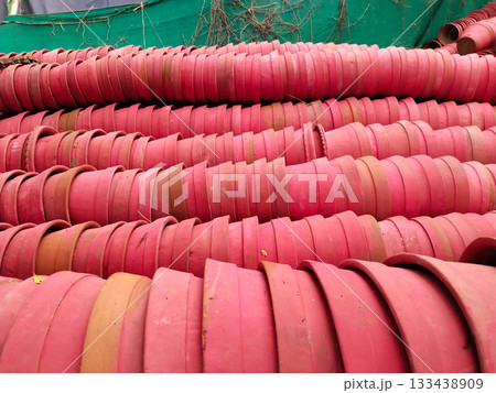 Rows of empty terracotta plant pots stacked in bulk, classic red clay planters prepared for gardening in outdoor storage area 133438909