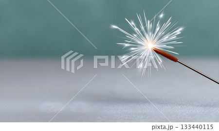 Close-up lit sparkler bursting with bright sparks on a soft teal background 133440115