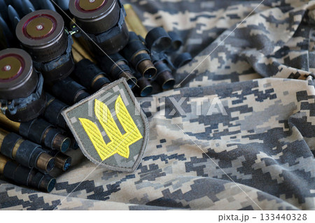 Ukrainian army symbol on machine gun belt lies on ukrainian pixeled military camouflage close up Ukrainian army symbol on machine gun belt lies on ukrainian pixeled military camouflage close up 133440328