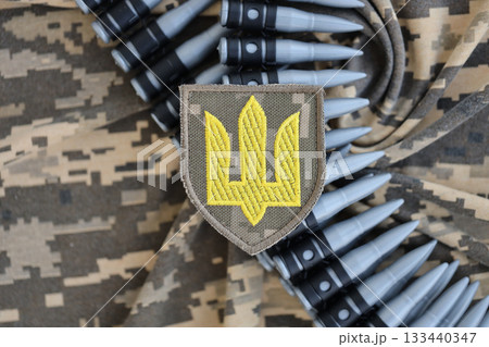 Ukrainian army symbol on machine gun belt lies on ukrainian pixeled military camouflage close up Ukrainian army symbol on machine gun belt lies on ukrainian pixeled military camouflage close up 133440347