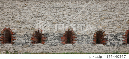 Very old window in brick stone wall of castle or fortress of 18th century. Full frame wall with window close up Very old window in brick stone wall of castle or fortress of 18th century. Full frame wall with window close up 133440367