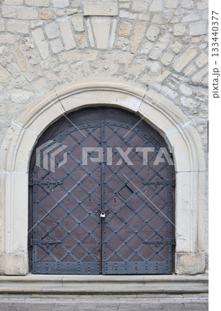 Very old solid door in brick stone wall of castle or fortress of 18th century. Full frame wall with door close up Very old solid door in brick stone wall of castle or fortress of 18th century. Full frame wall with door close up 133440377