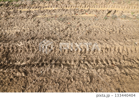 Wheel track on mud. Traces of a tractor or heavy off-road car on brown mud in a wet meadow 133440404