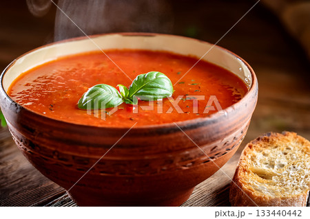木製テーブルの上のトマトスープと一切れのパン 133440442