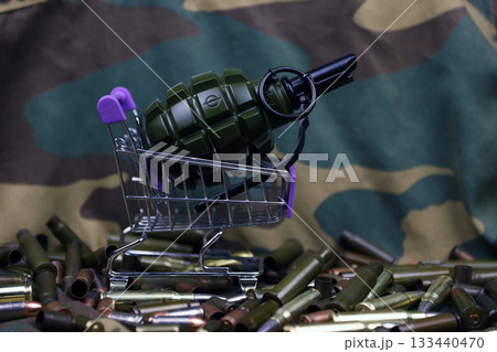 Rifle cartridges in small shopping cart. Big caliber ammo cartridges and hand grenades with a small shopping basket close up Rifle cartridges in small shopping cart. Big caliber ammo cartridges and hand grenades with a small shopping basket close up 133440470