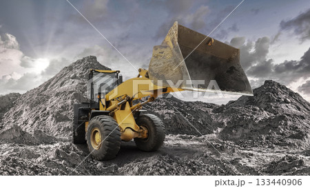 A loader works efficiently to shift large piles of dirt and debris at a busy construction site during late afternoon with dramatic clouds overhead 133440906