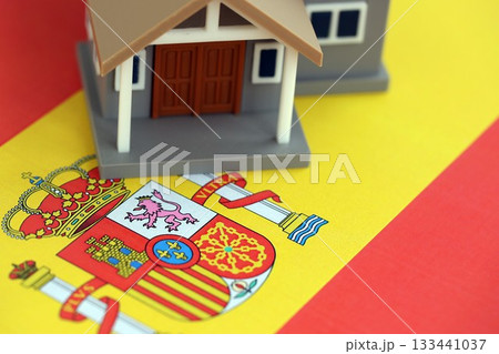 Residential house on Spanish flag close up. Concept of Squatting in Spain. Okupas problem Residential house on Spanish flag close up. Concept of Squatting in Spain. Okupas problem 133441037