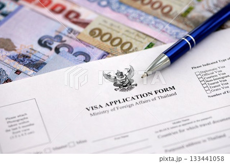 Visa application form to enter Thailand on table with pen and thai money bills close up Visa application form to enter Thailand on table with pen and thai money bills close up 133441058