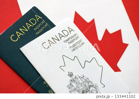 Canadian temporary and permanent passports lies on flag close up Canadian temporary and permanent passports lies on flag close up 133441102