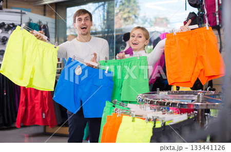 Husband and wife choose summer shorts together in clothing store 133441126