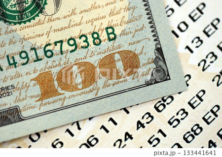 Lottery ticket and one hundred US dollar bill close up. Concept of gambling addiction and lottery 133441641