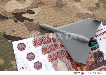 Russian money with bullets and kamikaze drone on multicam camouflage fabric close up. Concept of russian army funds and invasion to Ukraine 133441660