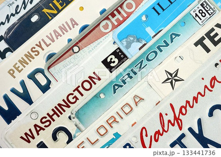 Old US car license plates with various state names. Concept of driving in United States. Reaching a car registration Old US car license plates with various state names. Concept of driving in United States. Reaching a car registration 133441736