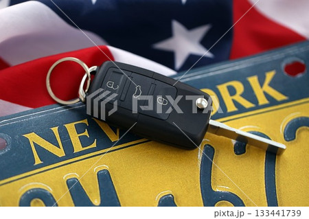 Remote control car keys on New York license plate on US flag. Concept of driving in New York. Reaching a driving permit Remote control car keys on New York license plate on US flag. Concept of driving in New York. Reaching a driving permit 133441739