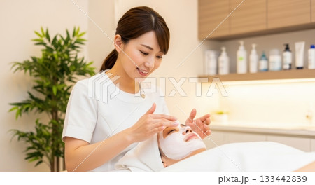 エステサロンでフェイスマッサージとパックを受ける笑顔の女性 133442839