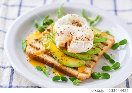 Breakfast with poached egg toast with avocado, vegetarian food.Healthy sandwich with avocado and poached eggs. 133444422