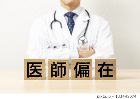 「医師偏在」と書かれたブロックと腕組みをする医師 「医師偏在」と書かれたブロックと腕組みをする医師 133445074
