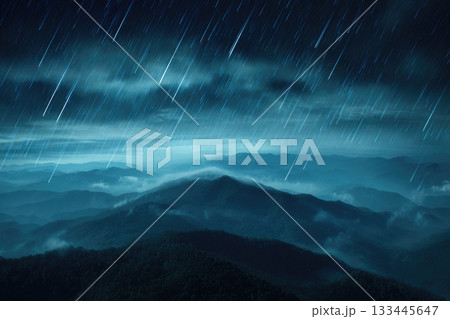 Rain falling over misty mountain landscape with blurred clouds, dramatic night sky, and defocused lightning storm, creating moody and atmospheric scene 133445647