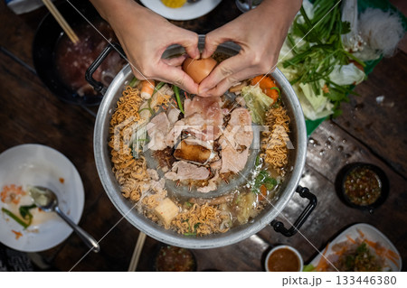 Sliced meat and vegetables cook in a metal grill pot filled with broth and steam, while the center grill browns the meat. Sliced meat and vegetables cook in a metal grill pot filled with broth and steam, while the center grill browns the meat. 133446380