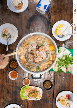 Sliced meat and vegetables cook in a metal grill pot filled with broth and steam, while the center grill browns the meat. Sliced meat and vegetables cook in a metal grill pot filled with broth and steam, while the center grill browns the meat. 133446383
