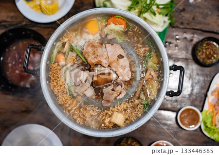 Sliced meat and vegetables cook in a metal grill pot filled with broth and steam, while the center grill browns the meat. Sliced meat and vegetables cook in a metal grill pot filled with broth and steam, while the center grill browns the meat. 133446385