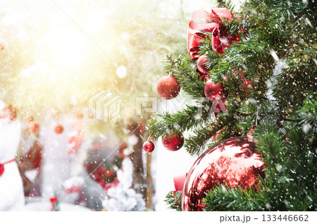 Red baubles on pine trees and falling snow. Winter, Christmas and New Year festival. 133446662
