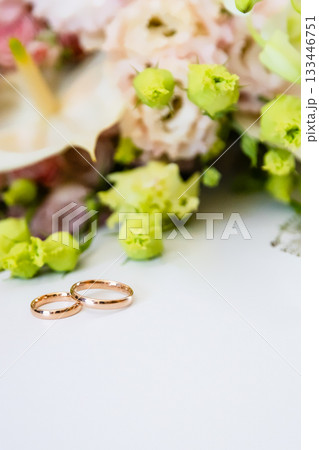 pair of gold wedding rings lie on white paper 133446751