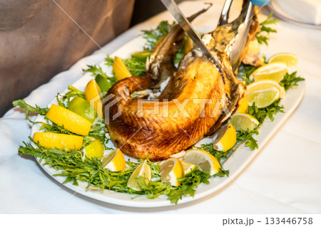 cutting baked sturgeon on platter on table cutting baked sturgeon on platter on table 133446758