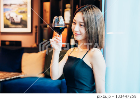 ラグジュアリーな雰囲気のお店で赤ワインを飲む若い女性 ラグジュアリーな雰囲気のお店で赤ワインを飲む若い女性 133447259