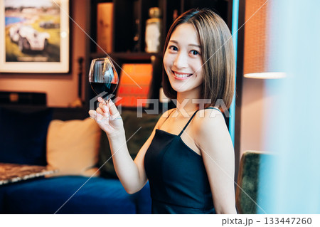 ラグジュアリーな雰囲気のお店で赤ワインを飲む若い女性 133447260