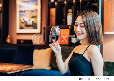 ラグジュアリーな雰囲気のお店で赤ワインを飲む若い女性 ラグジュアリーな雰囲気のお店で赤ワインを飲む若い女性 133447261