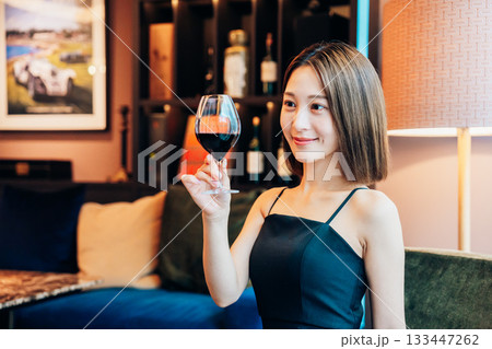 ラグジュアリーな雰囲気のお店で赤ワインを飲む若い女性 ラグジュアリーな雰囲気のお店で赤ワインを飲む若い女性 133447262