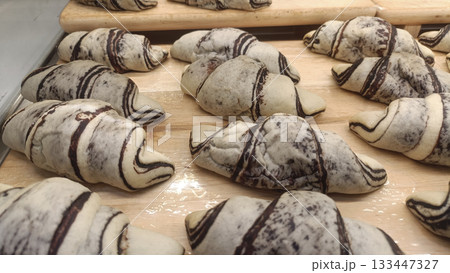 Marbled chocolate croissant on wooden tray, fresh pastry with swirled dough, warm tempting baked aroma 133447327