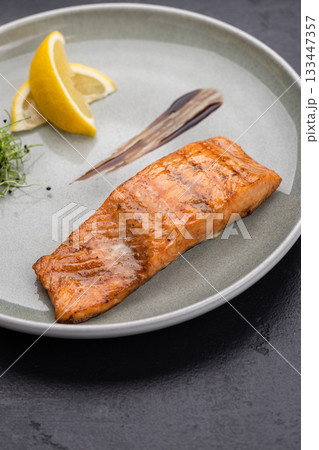Grilled salmon fillet with lemon and microgreens on plate, gourmet restaurant plating Grilled salmon fillet with lemon and microgreens on plate, gourmet restaurant plating 133447357