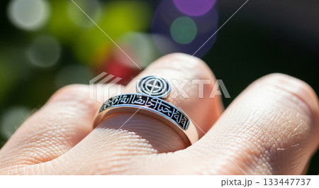 Close-up view of the Baha'i Ringstone symbol engraved on a simple ring highlights the intricate calligraphy. The sunlight enhances the details beautifully. Close-up view of the Baha'i Ringstone symbol engraved on a simple ring highlights the intricate calligraphy. The sunlight enhances the details beautifully. 133447737