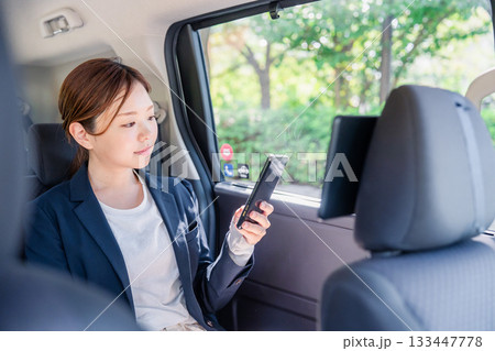 タクシーでスマホを使う若い女性ビジネスパーソン 133447778